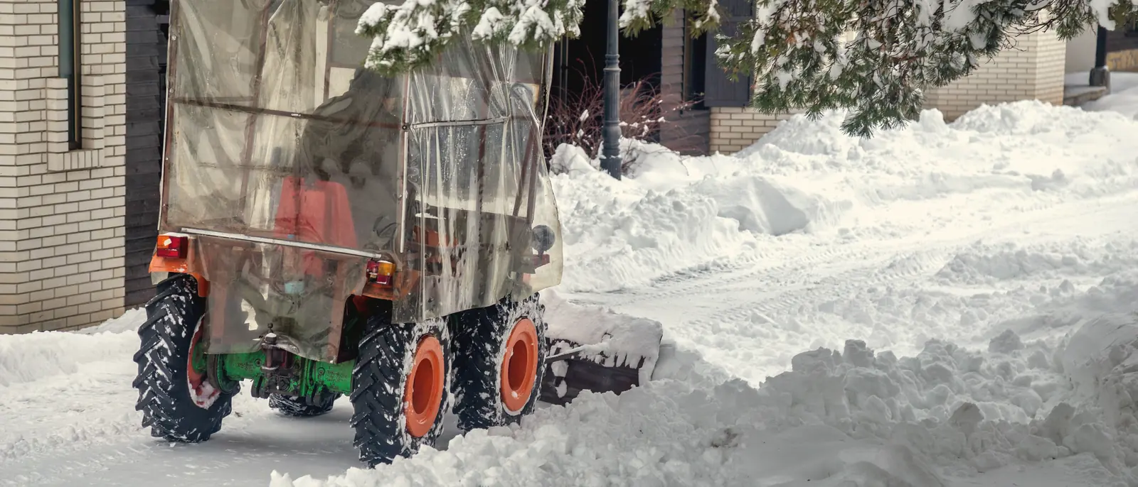 Tracteur à souffleuse déneigeant une entrée résidentielle