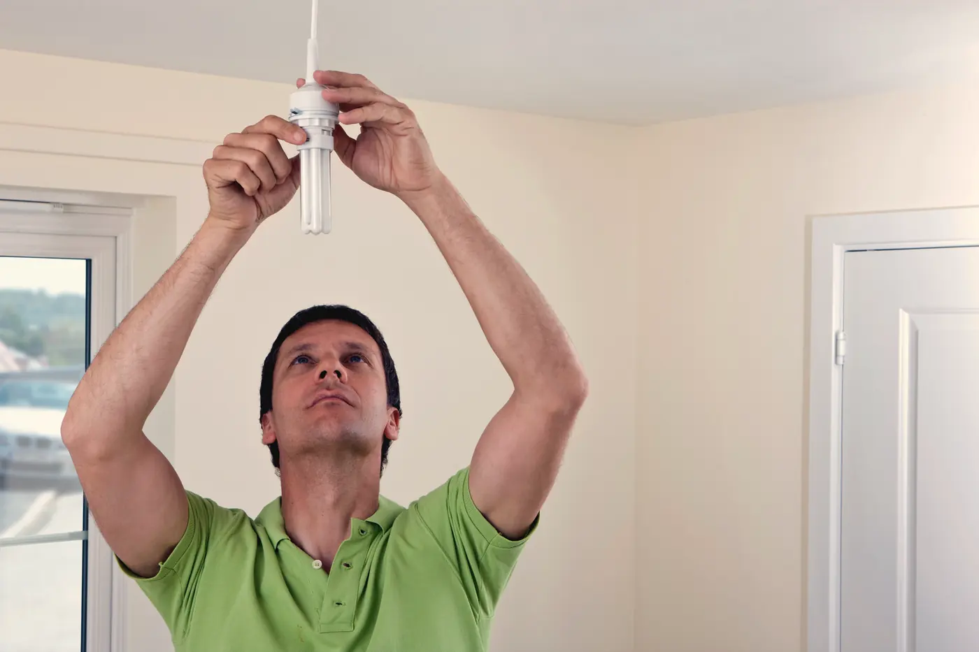 Électricien installant un luminaire au plafond