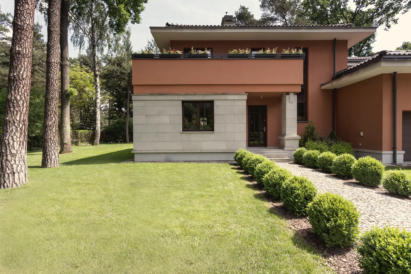 Maison contemporaine avec aménagement paysager haut de gamme : haies taillées et pelouse impeccable