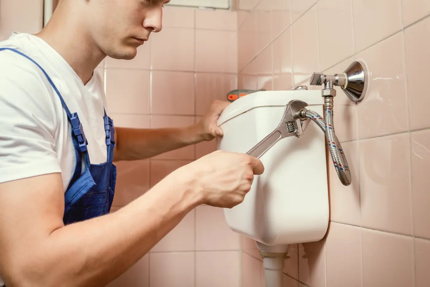 Plombier réparant le réservoir d'une toilette